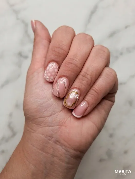Uñas delicadas en tonos nude con destellos dorad...