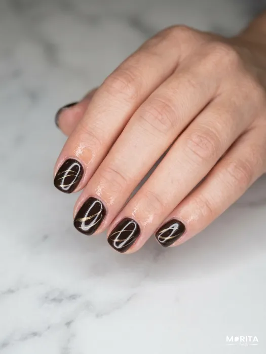 Uñas minimalistas en dorado sobre un fondo negro...