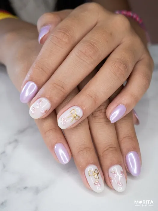 Uñas lila con un lazo dorado y mini fresitas par...